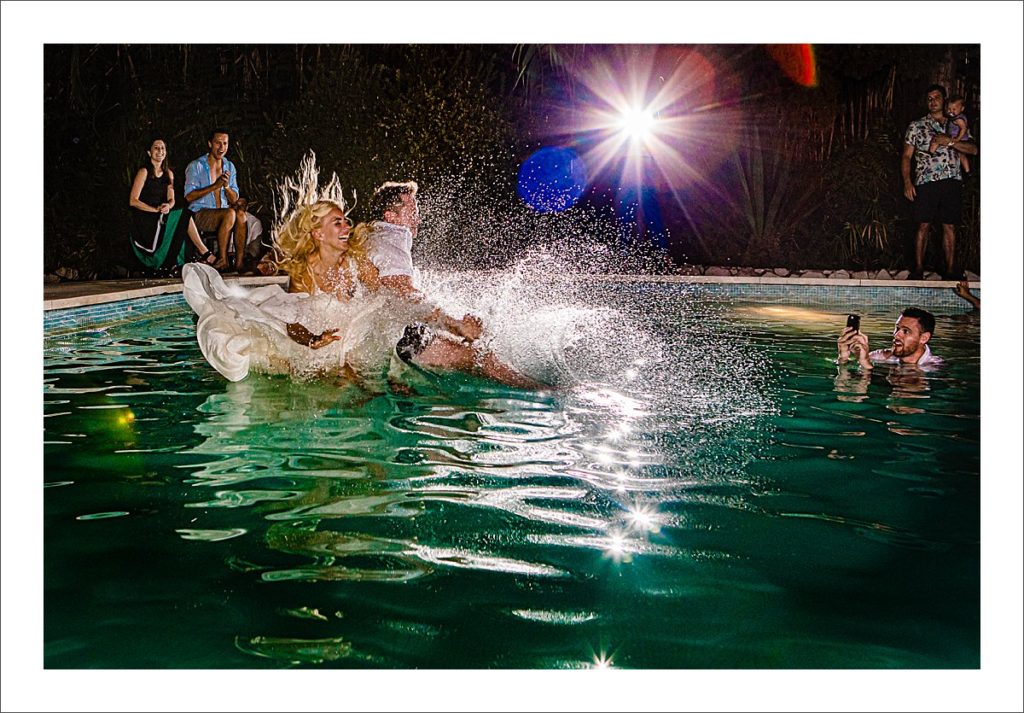 bride and groom jump in the pool