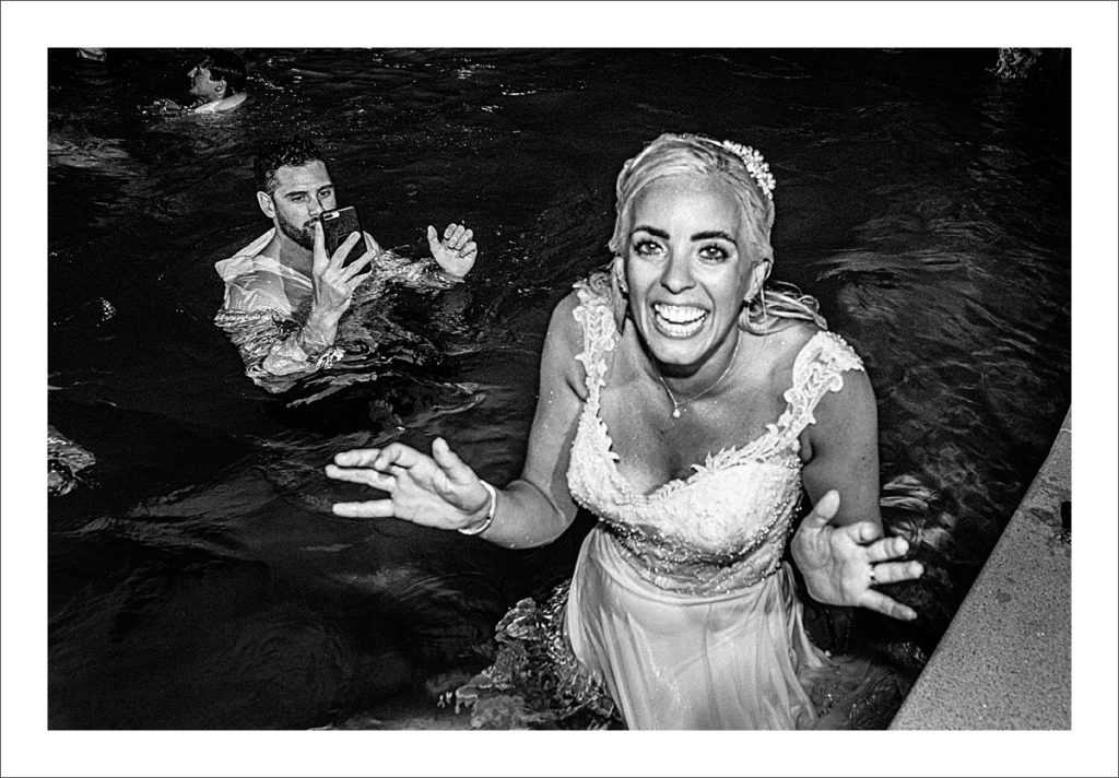 bride and groom jump in the pool